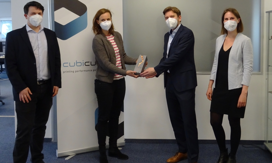 Vier Personen stehen nebeneinander. Die Urkunde für den Exportpreis Bronze wird von einer Vertreterin der WKO an den Geschäftsführer der Cubicure GmbH überreicht.